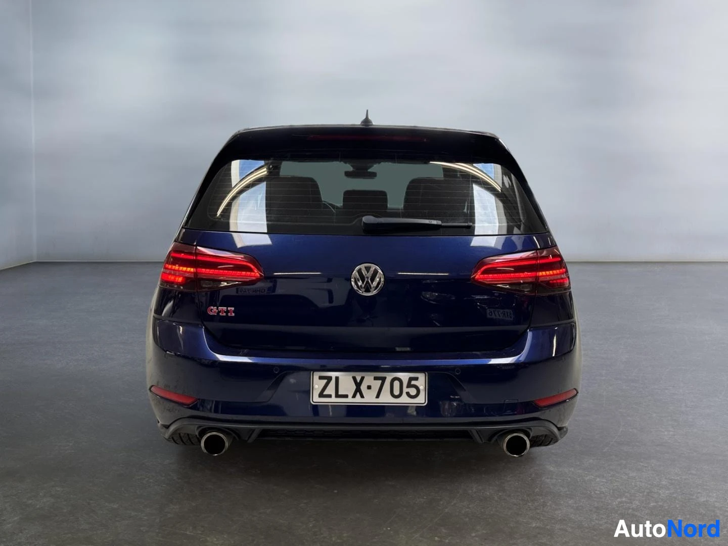 Takaa: Tummansininen Volkswagen Golf GTI suoraan takaa kuvattuna, rekisteritunnus, kaksi pakoputkea ja GTI-merkintä.