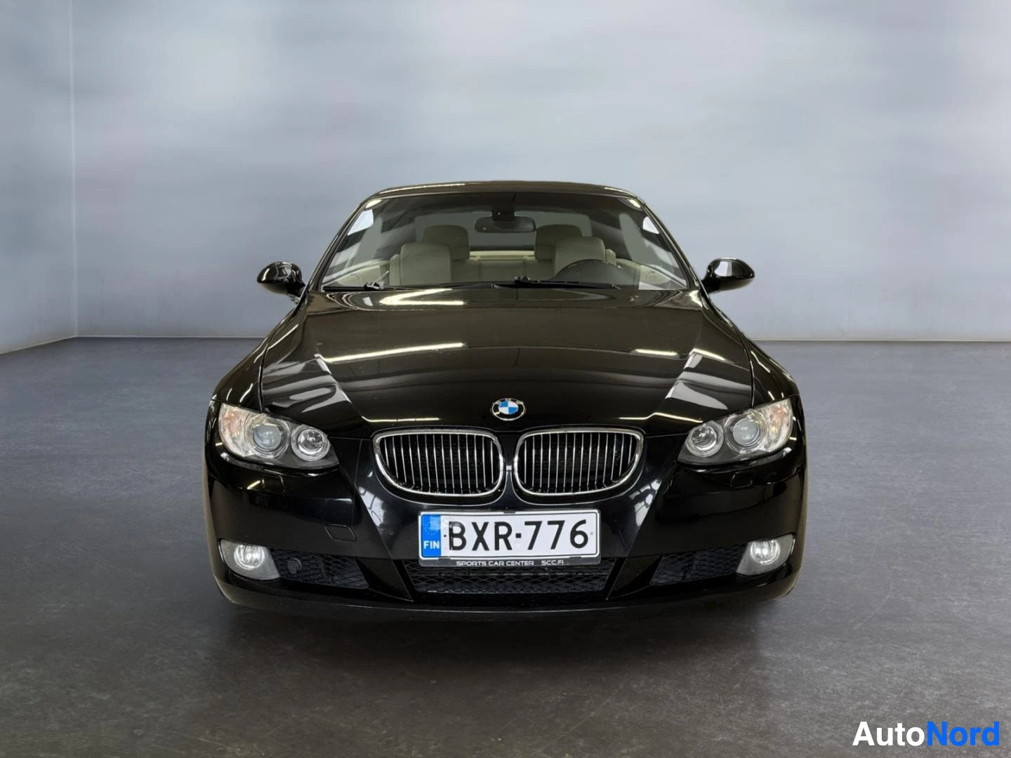 Edestä: Mustan auton suora etunäkymä, BMW-merkki ja rekisterikilpi.