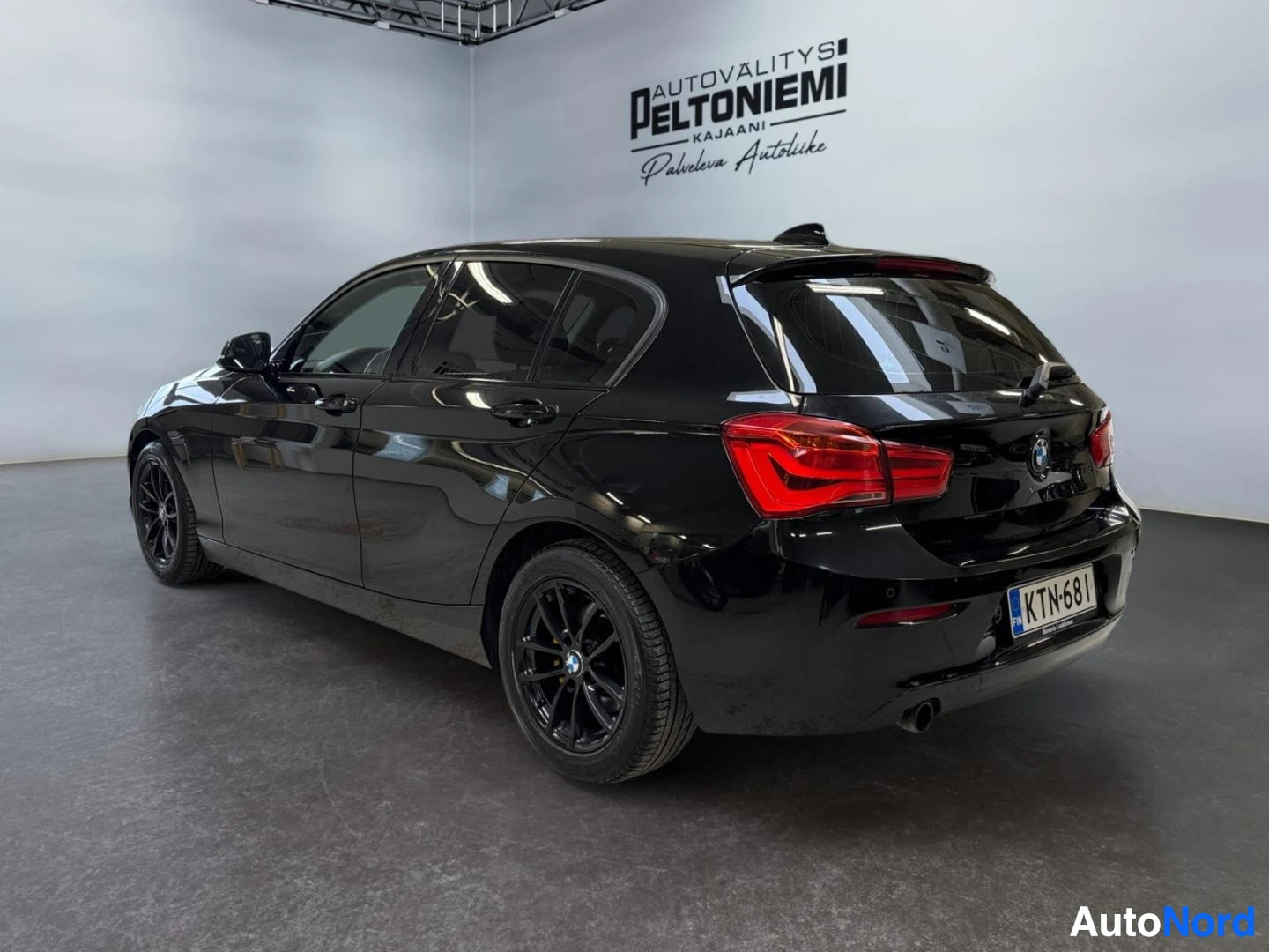 Takaviisto: Musta BMW 1-sarjan viistosti takaa oikealta; punaiset takavalot, takapuskuri ja -rekisterikilpi.