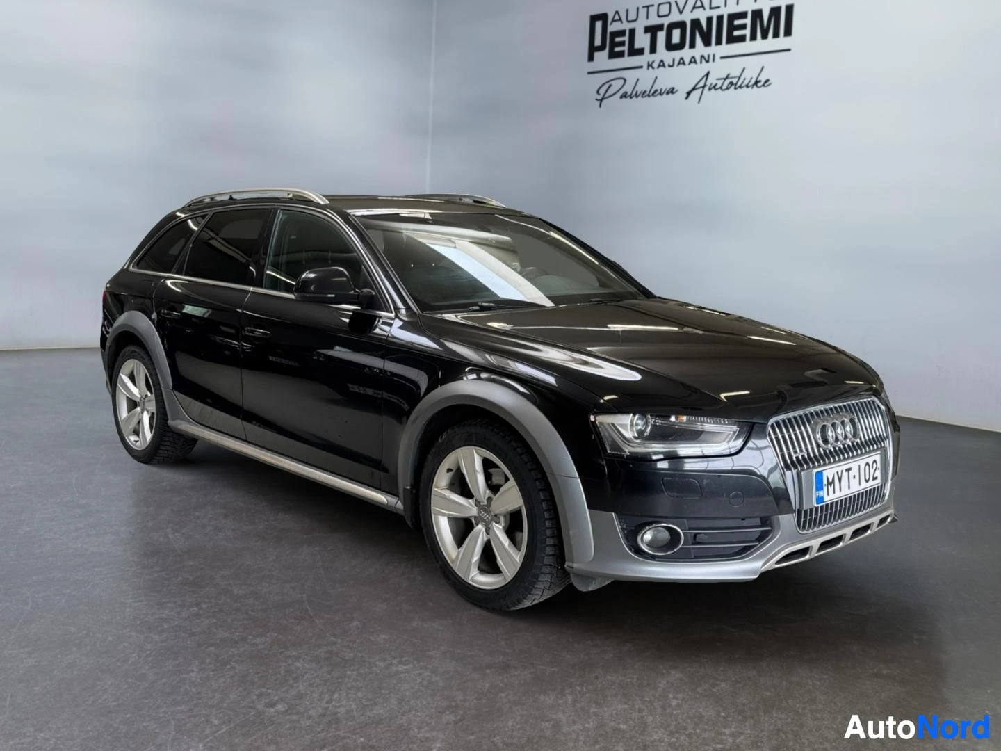 Etuviisto, nokka oikealle: Musta Audi A4 Allroad -farmari kolmella neljäsosaa edusta, keulakuva oikealla, hopeiset vanteet ja kattokaiteet.