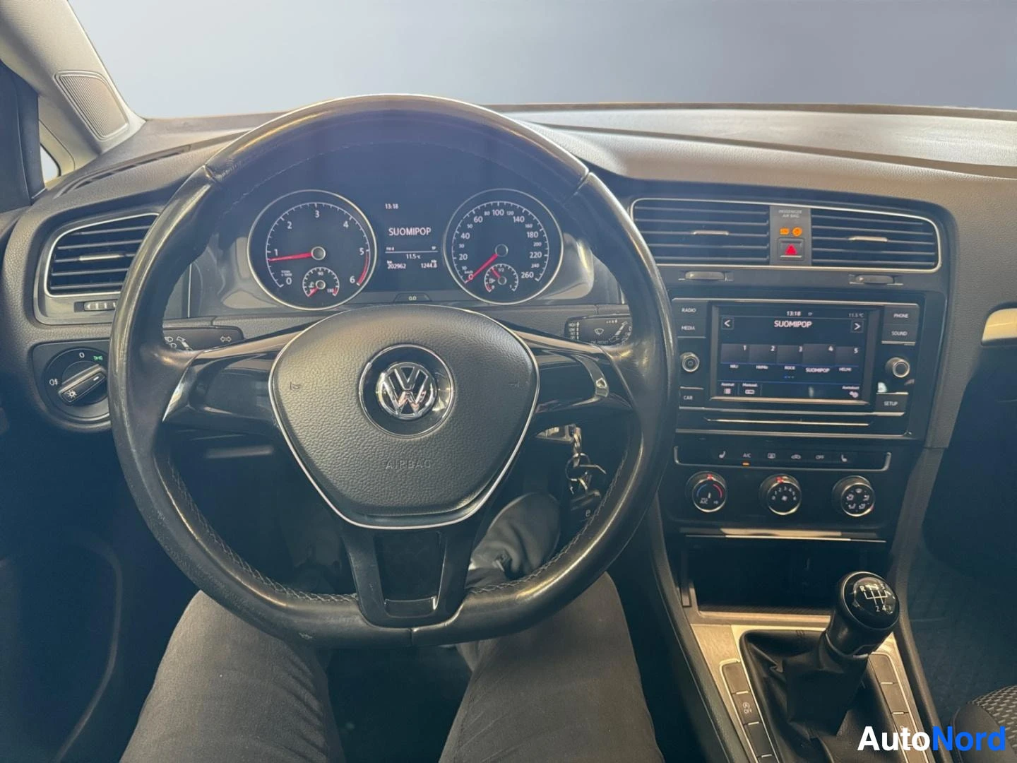 Muu: Volkswagen-merkkisen auton ohjaamo: ratin, kojelaudan ja radio-konsolin näkymä.