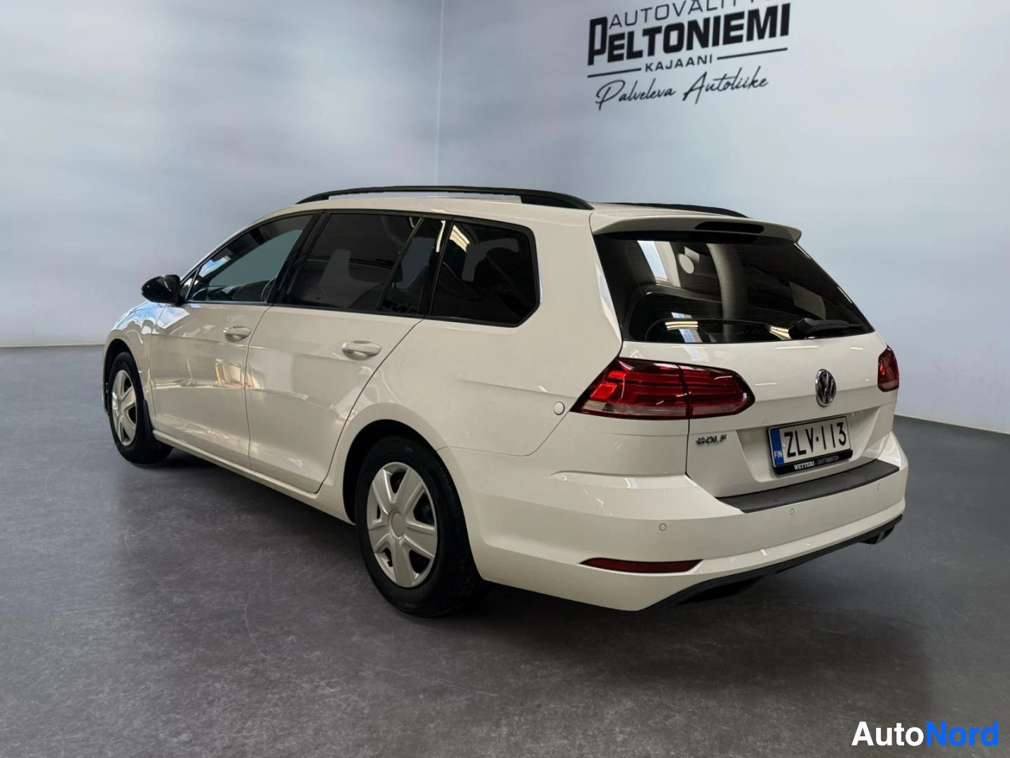 Takaviisto: Volkswagen Golf -farmarin takakulma valkoisena, takavalojen rekisterikilpi näkyvissä sisätiloissa.