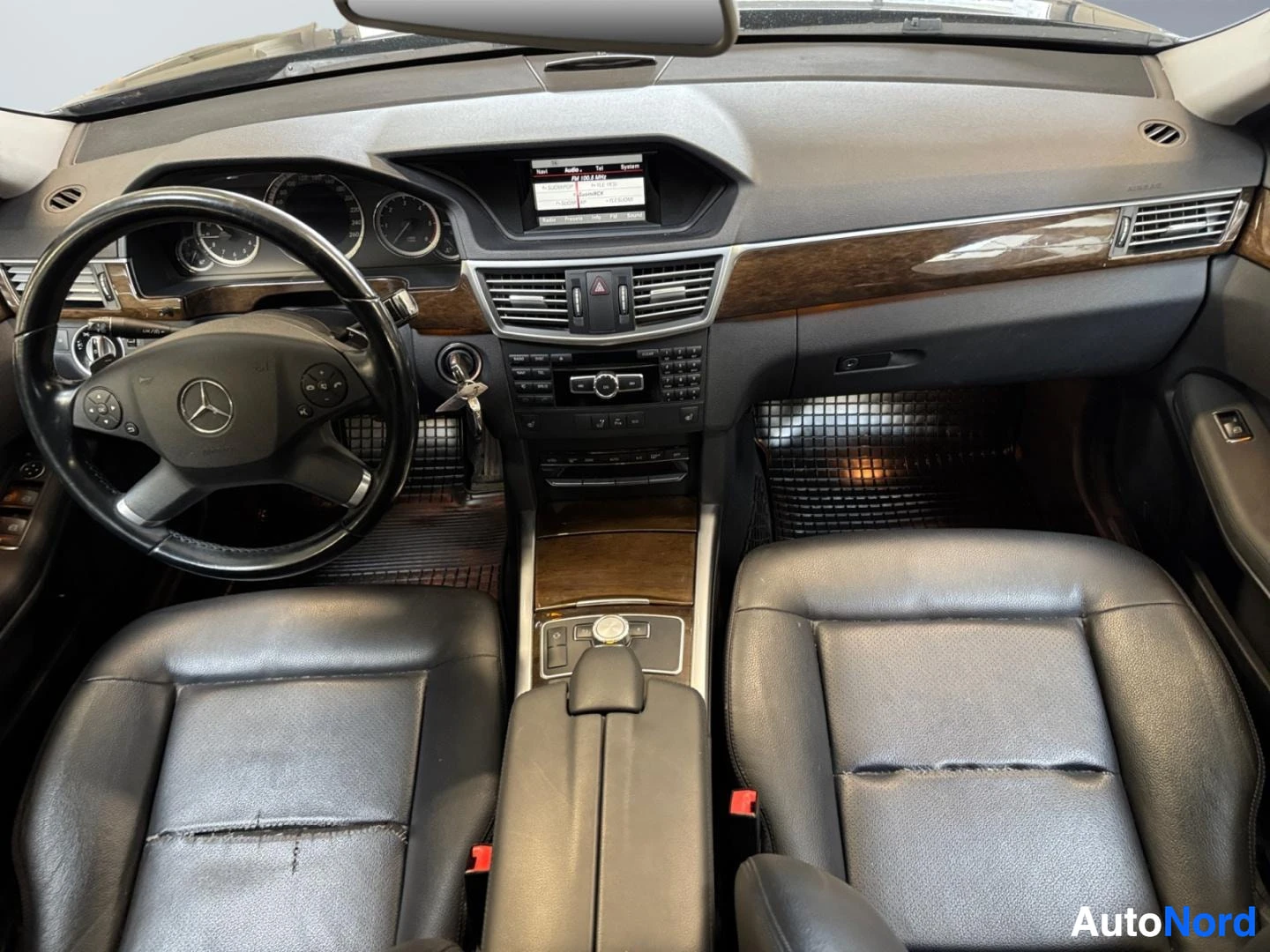 Muu: Kojelaudan näkymä ylhäältä: ohjauspyörä Mercedes-tähdellä, mittaristo, keskikonsolin näyttö ja radio, mustat nahkaistuimet.