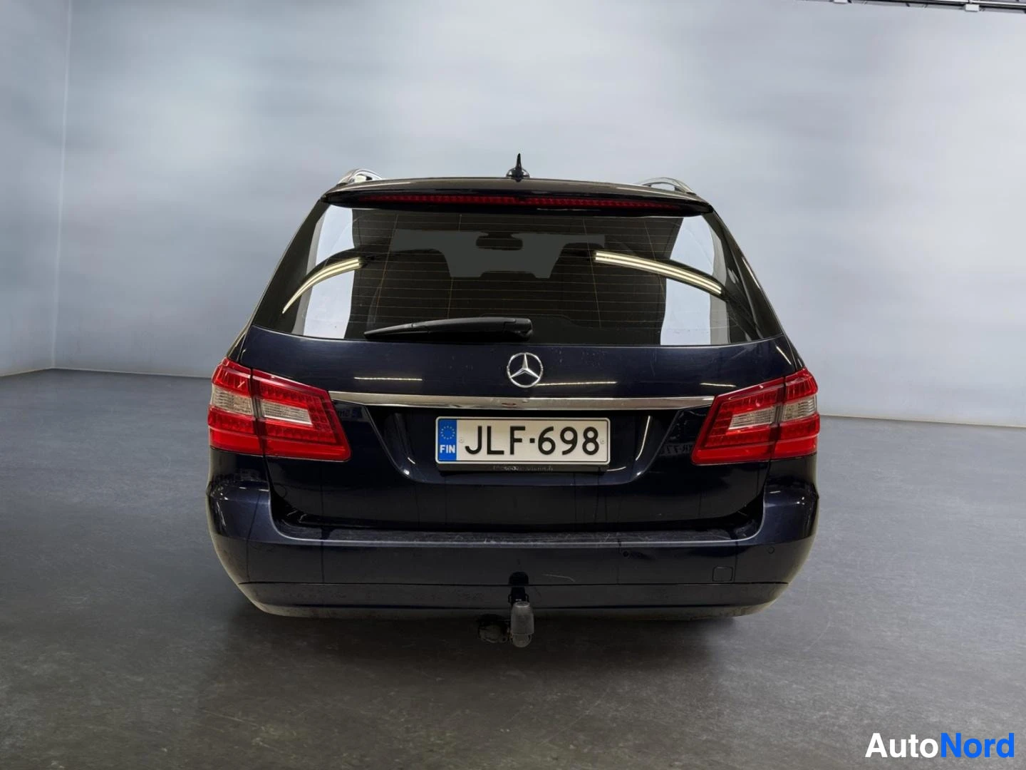Takaa: Mercedes-Benzfarmari suoraan takaa, rekisteritunnus, tummansininen korimalli studiosta.