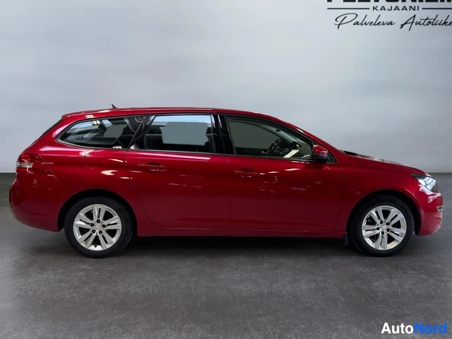 Sivulta: Punaisen Peugeot 308 SW:n sivuprofiili oikealta sivulta näyttämössä.