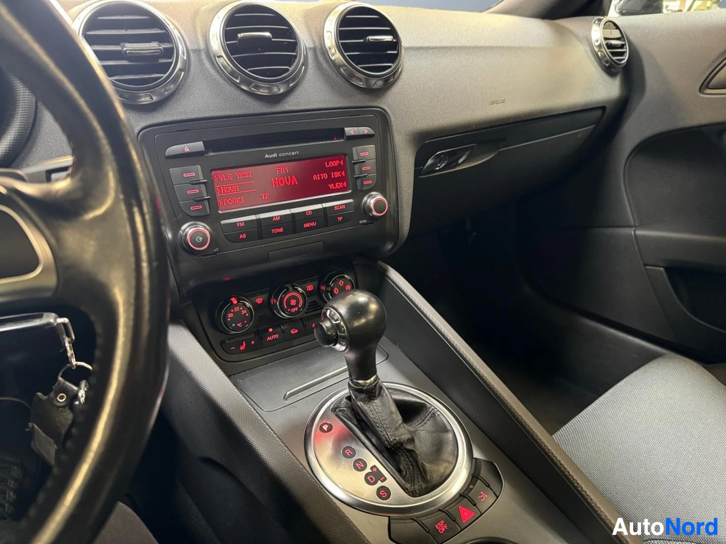 Ohjaamo: Keskikonsoli lähikuvassa: Audi concert -radio, automaattivaihteen valitsin ja ilmastoinnin säätimet.