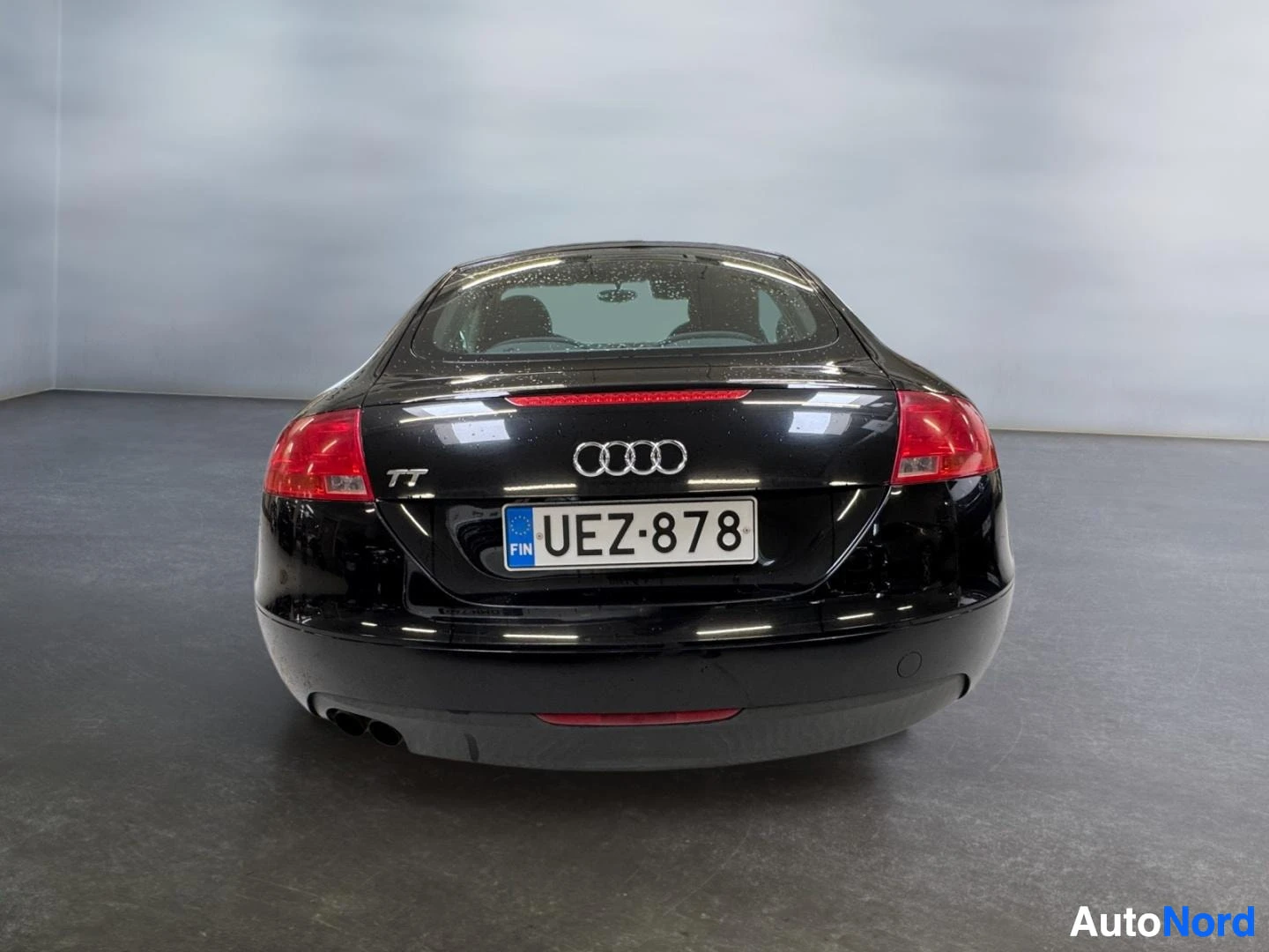 Takaa: Audi TT Coupé mustana suoraan takaa, rekisterikilpi ja tuplapakoputket näkyvissä.