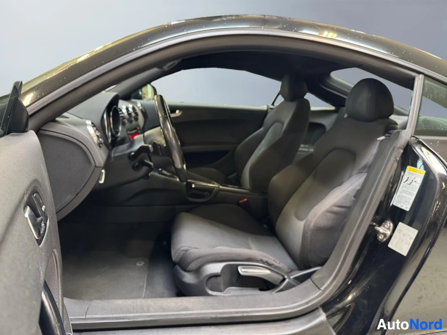 Muu: Audi TT:n kuljettajan puolen sisätila: kangasistuimet, ohjauspyörä ja kojelauta.
