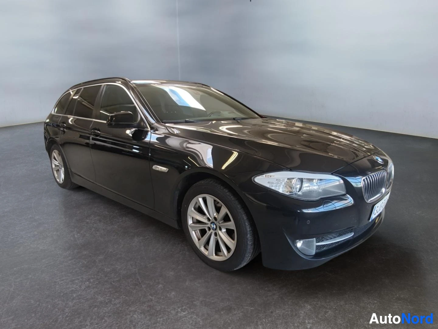 Etuviisto, nokka oikealle: Mustan BMW 5-sarjan farmarin etukolmannäs Vasemmasta alas oikealle näkyvät keula ja kylki.