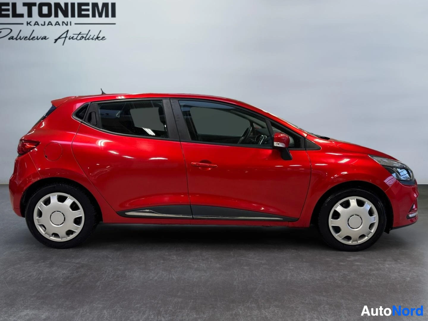Sivulta: Punaisen Renault Clion sivukuva autotallin sisällä.