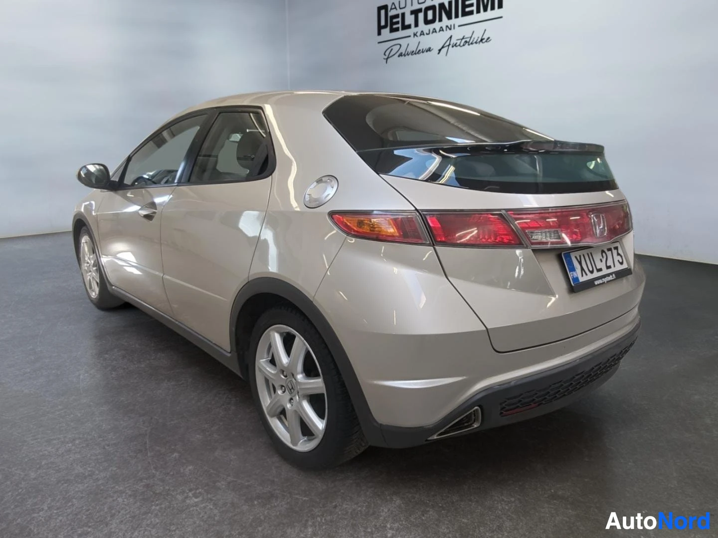 Takaviisto: Honda Civic Viistoperä takaa-vinosti kuvattuna, beige-kultainen koripelti, takavalot ja rekisterikilpi näkyvissä.
