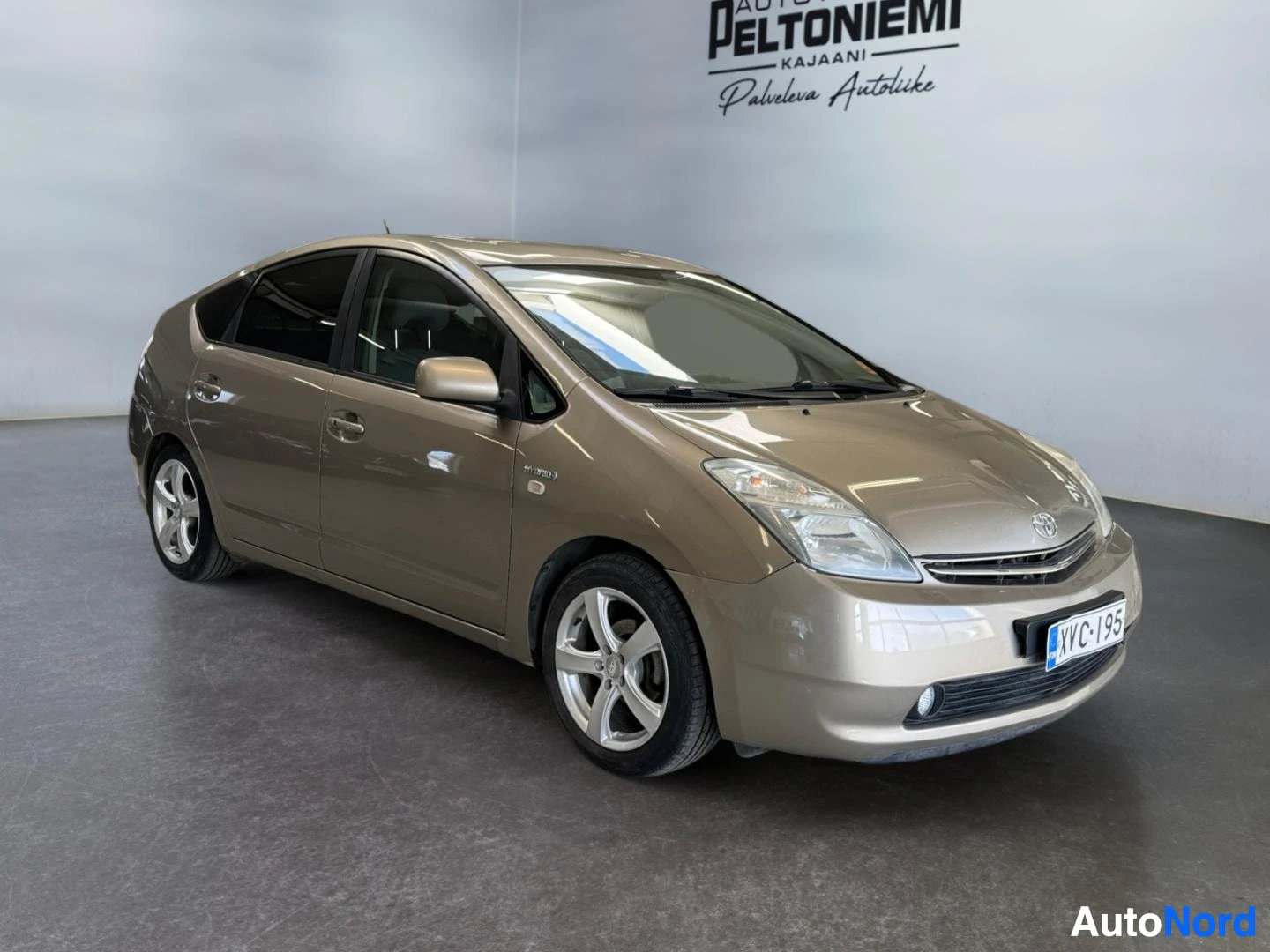 Etuviisto, nokka oikealle: Kultaisenbeige Toyota Prius vinosti edestä vasemmalta kuvattuna, rekisteri.