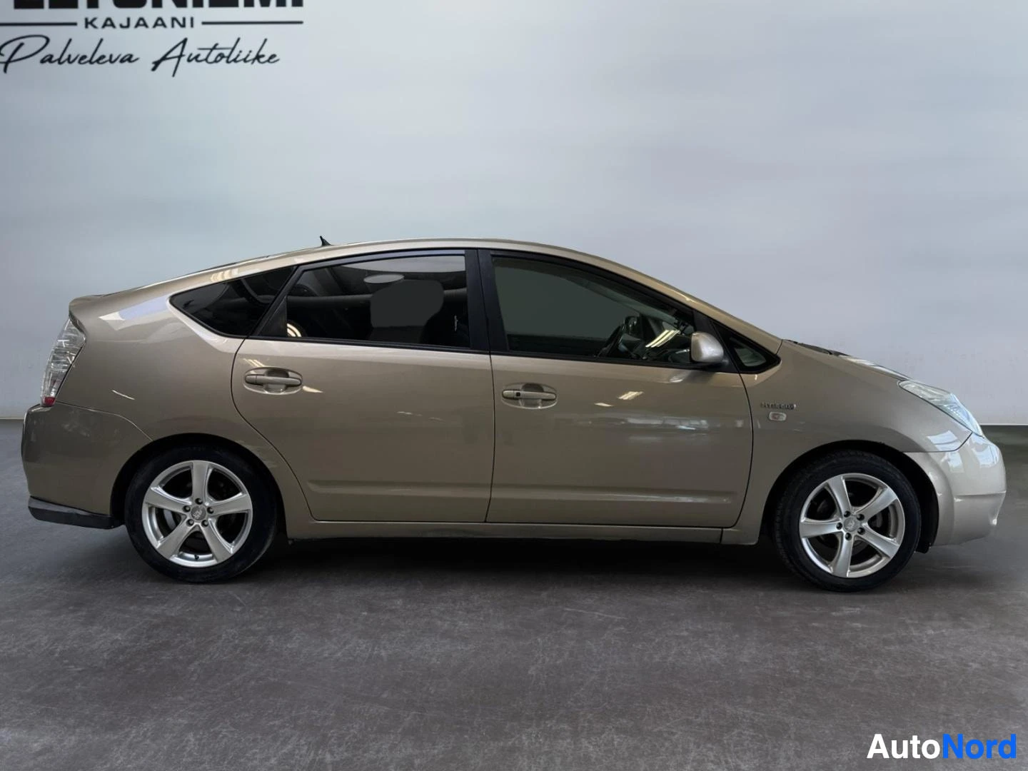 Sivulta: Kultaisenbeige Toyota Prius sivulta oikealta kuvattuna.
