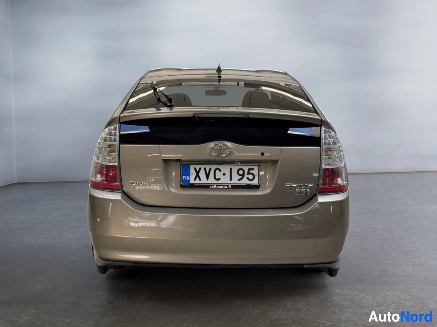 Takaa: Kultaisenbeige Toyota Prius suoraan takaa kuvattuna, rekisteri.