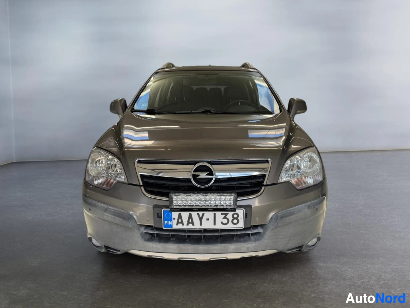 Edestä: Ruskeanharmaan auton suora etunäkymä, etusäleikössä Opel-merkki ja LED-apuvalot rekisterikilven yllä.
