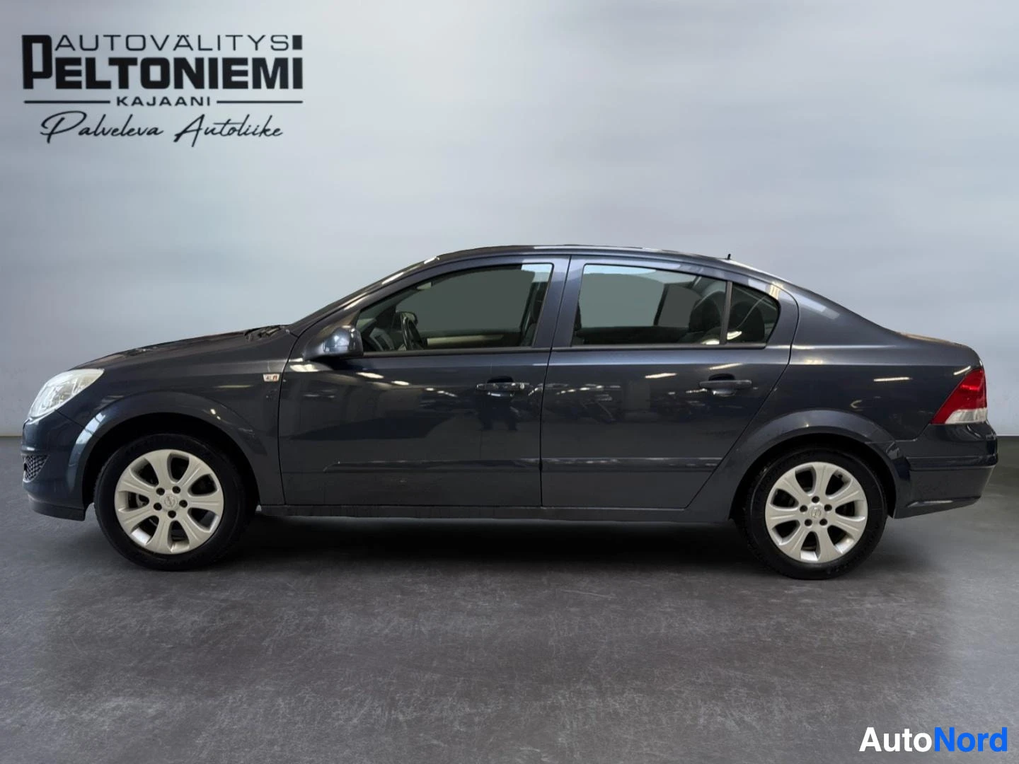 Takaviisto: Opel Astra -sedanin kylki kuvattuna sivusuunnassa, tummanharmaa koripelti ja hopeanväriset pyöränvanteet.