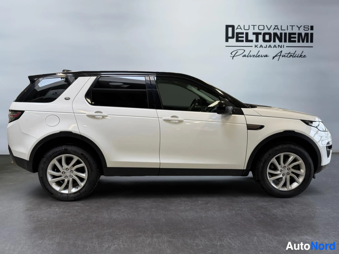 Sivulta: Land Rover Discovery Sport sivukuva vasemmalta, valkoinen kori, musta katto ja hopeat vanteet.