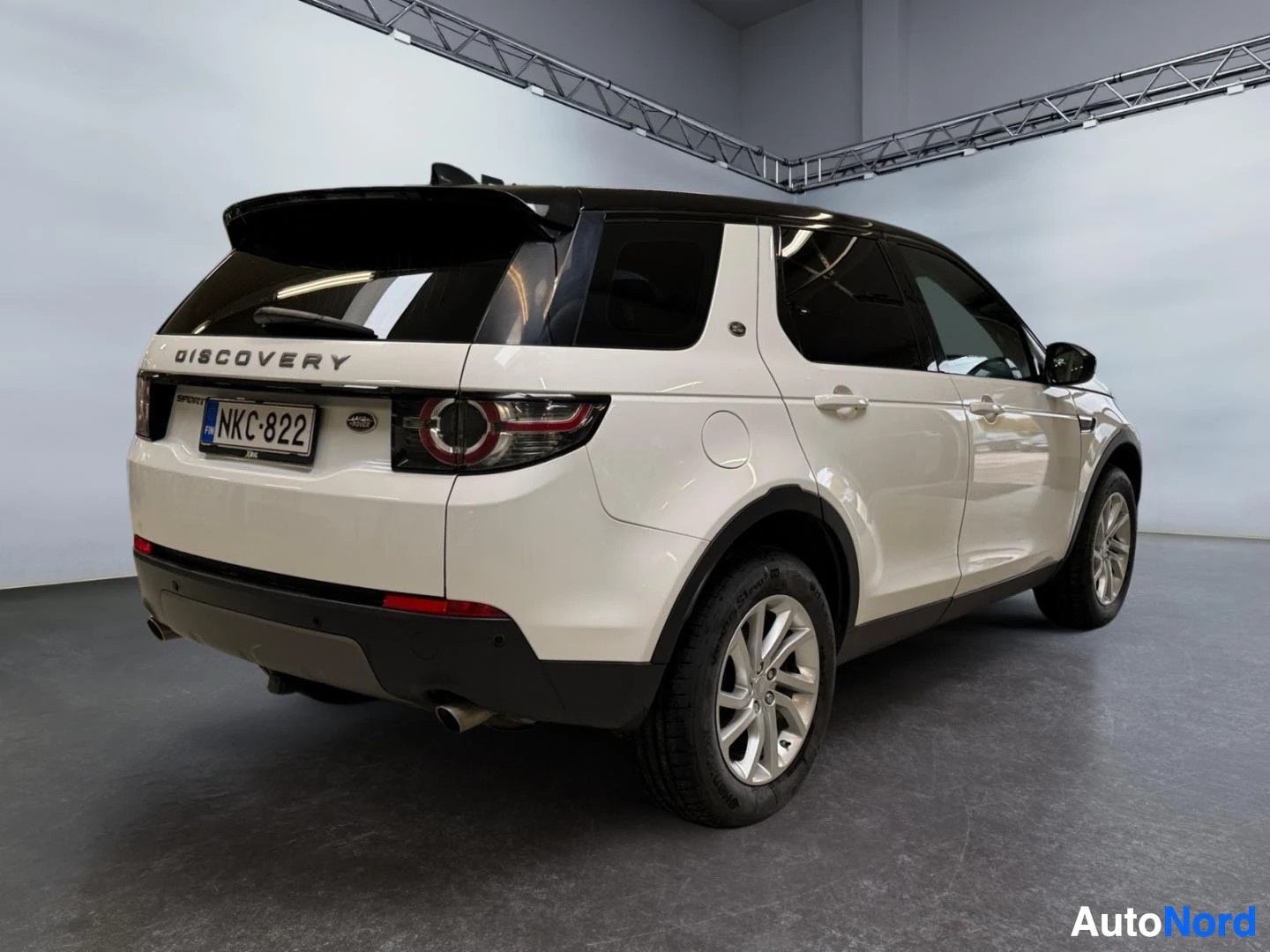 Takaviisto: Land Rover Discovery Sport takaviistokuva vasemmalta, valkoinen kori, musta katto ja takana DISCOVERY-teksti, rekisterikilpi.