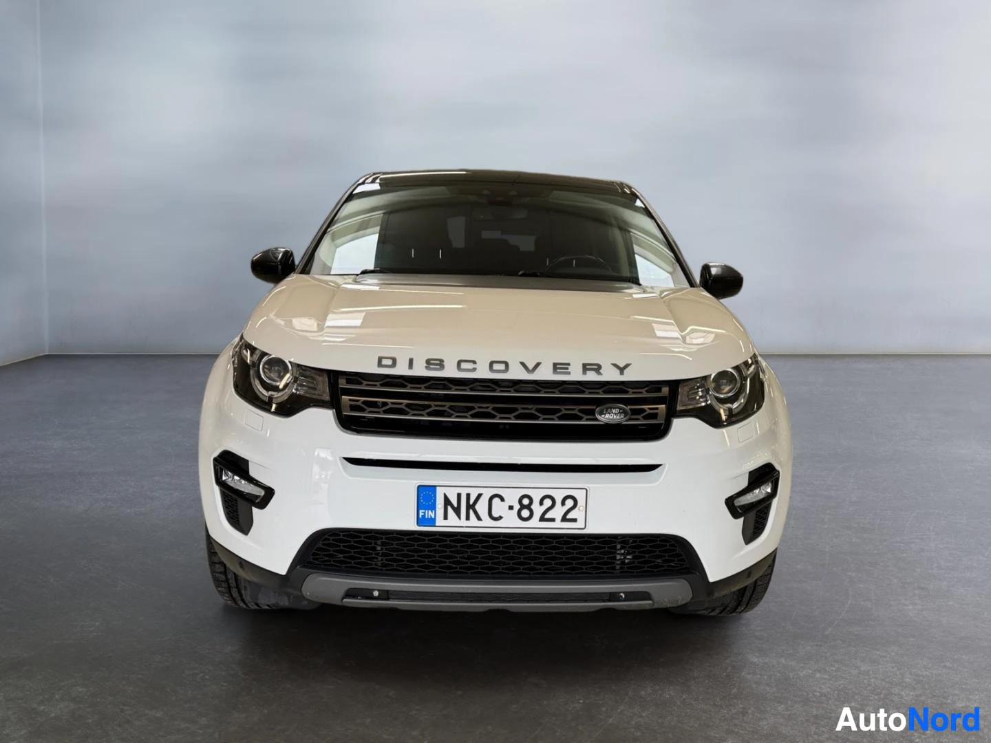 Edestä: Land Rover Discovery Sport, suora etukuva valkoisesta autosta, rekisterikilpi.