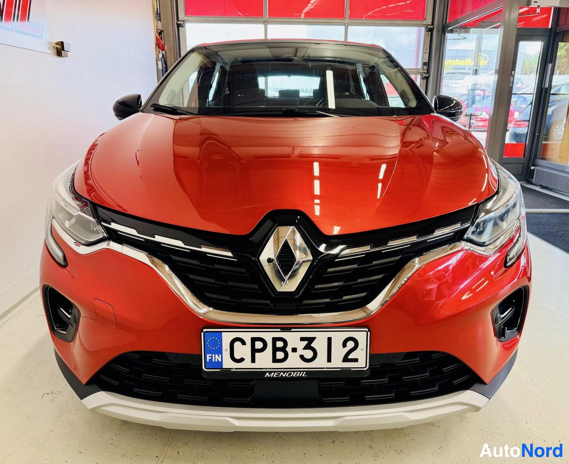Edestä: Punaisen Renault Capturin etunäkymä, rekisteritunnus ja Renault-logot jäähdyttimen säleikössä
