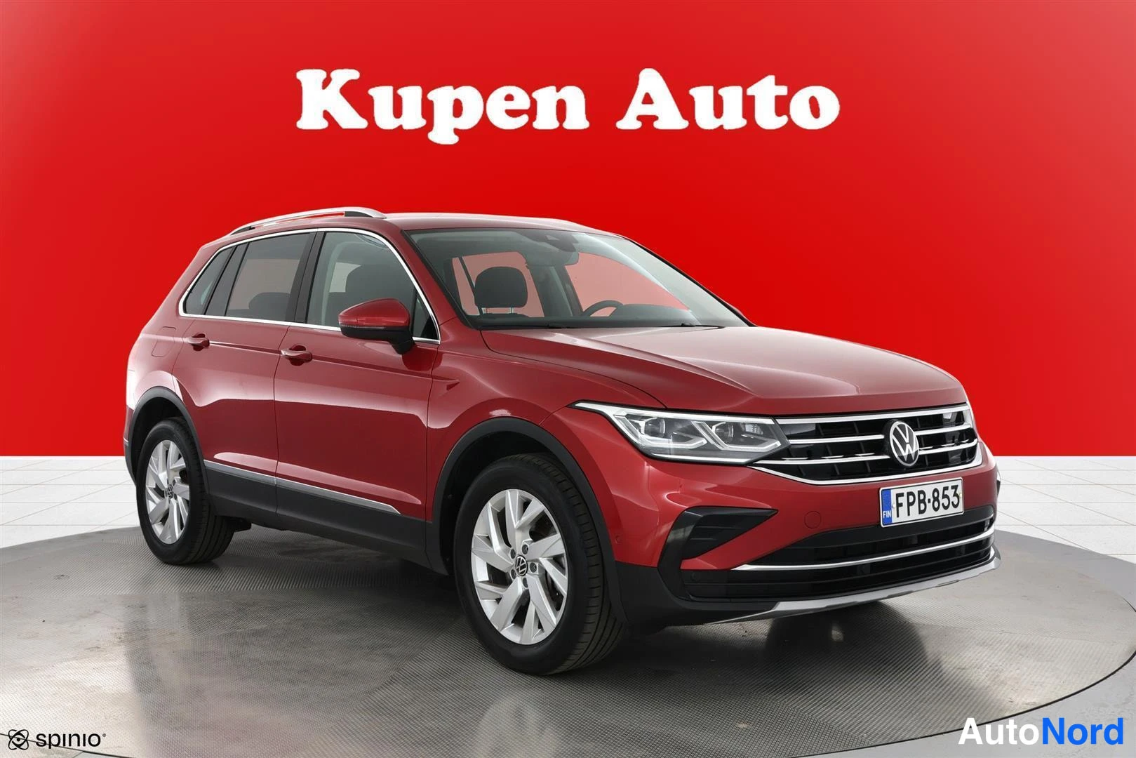 Etuviisto, nokka oikealle: Punainen Volkswagen Tiguan etukulmasta oikealta, rekisterikilpi, kattokaiteet ja alumiinivanteet näkyvissä.