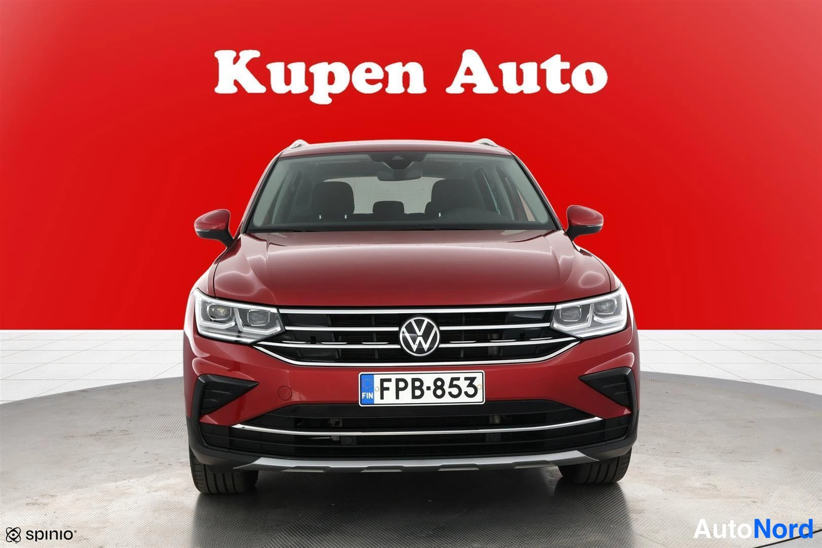 Edestä: Punaisen Volkswagen Tiguanin etunäkymä, VW-merkki ja rekisterikilpi.