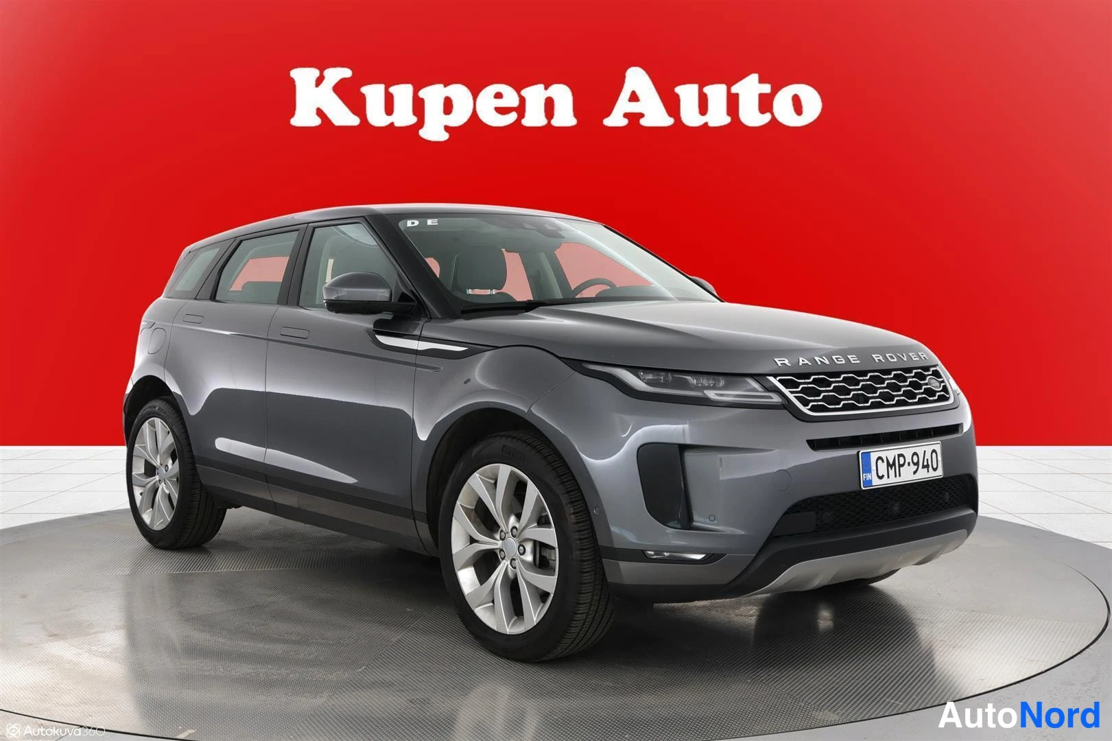 Etuviisto, nokka oikealle: Harmaa Range Rover Evoque kulmassa edestä oikealta, rekisteri, punainen tausta