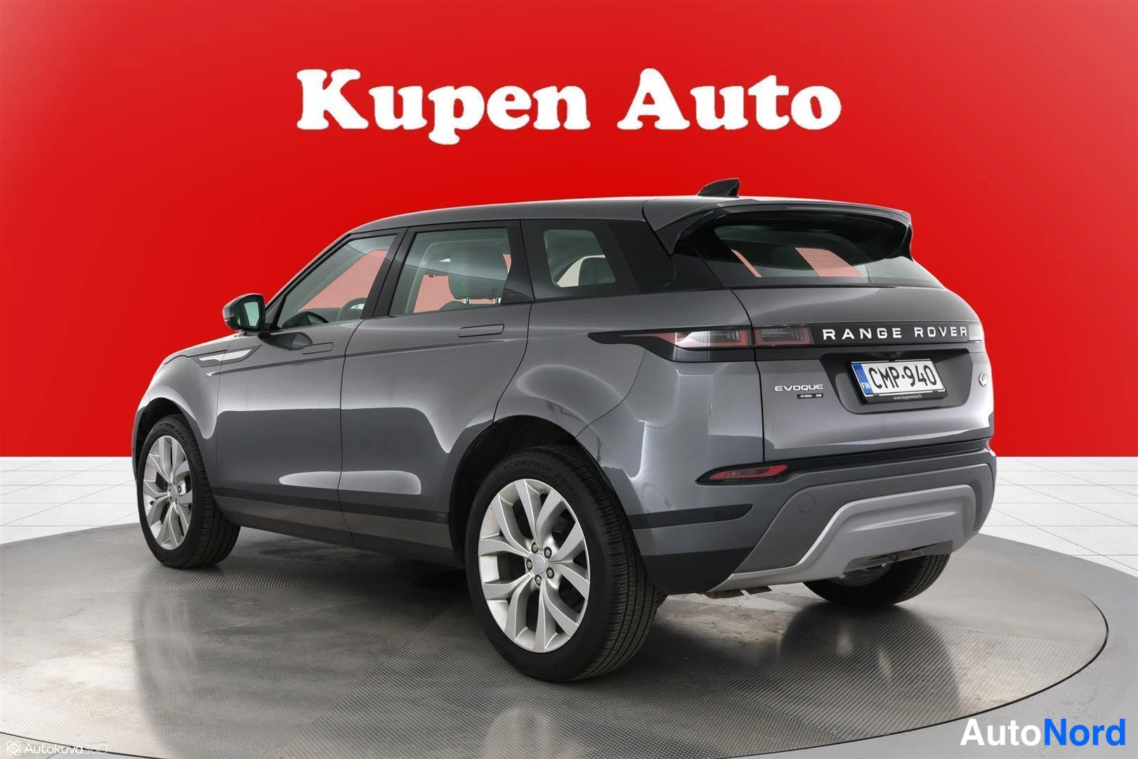 Takaviisto: Land Rover Range Rover Evoquein takaosakulmakuva vasemmalta, tummanharmaa koripinta ja hopeat vanteet punaisella taustalla