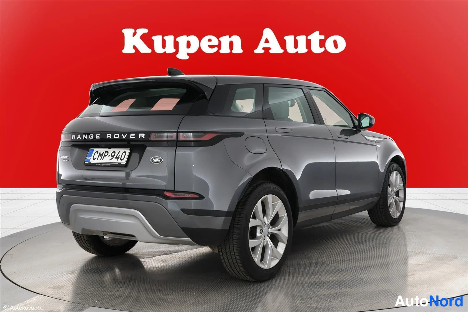 Takaviisto: Land Rover Range Rover Evoquein takaosakulmakuva oikealta, tummanharmaa koripinta ja hopeat vanteet punaisella taustalla