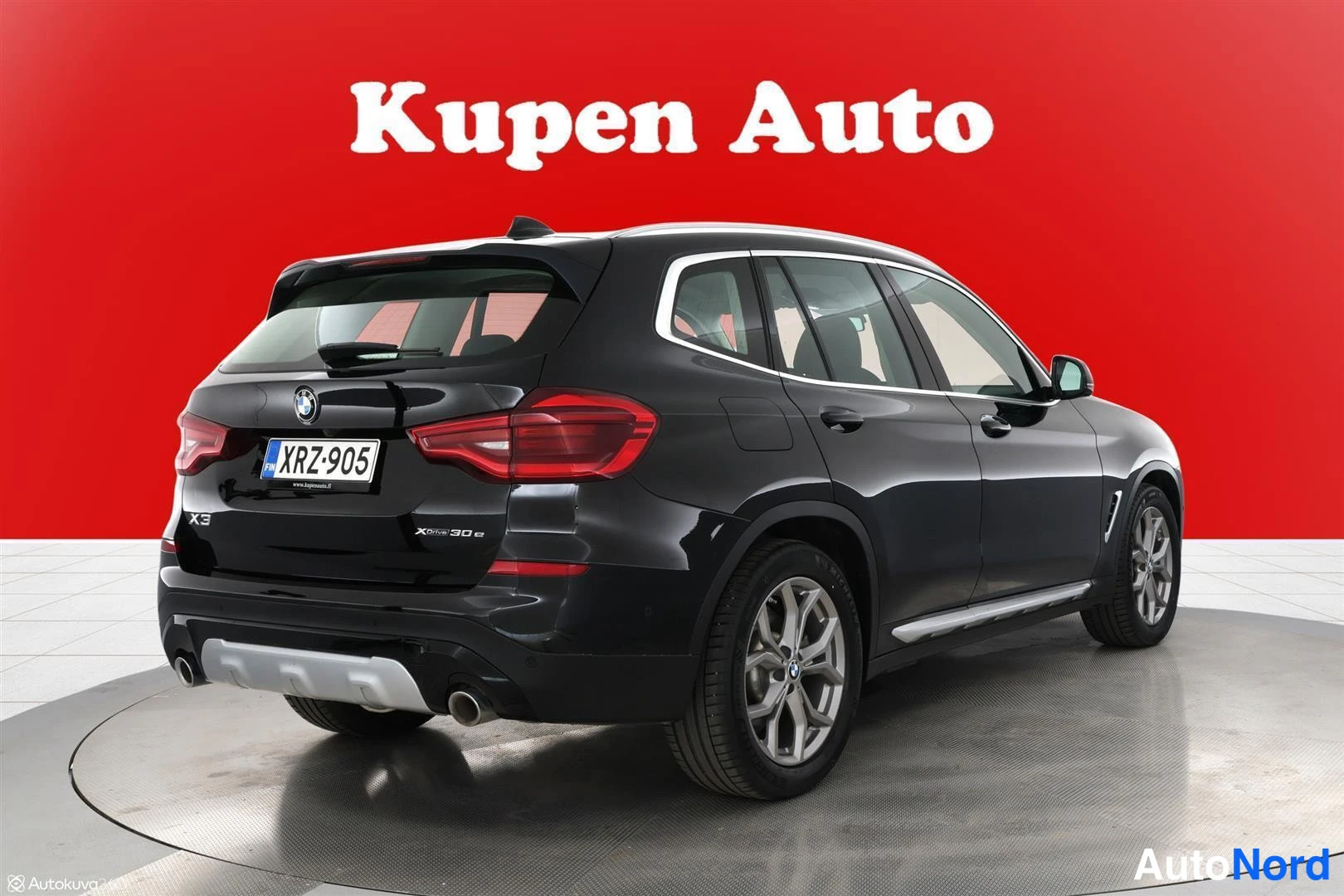 Takaviisto: Mustan BMW X3:n takaosa ja oikea kylki kolmesta neljänneksestä, hopeavanteet, punainen tausta.
