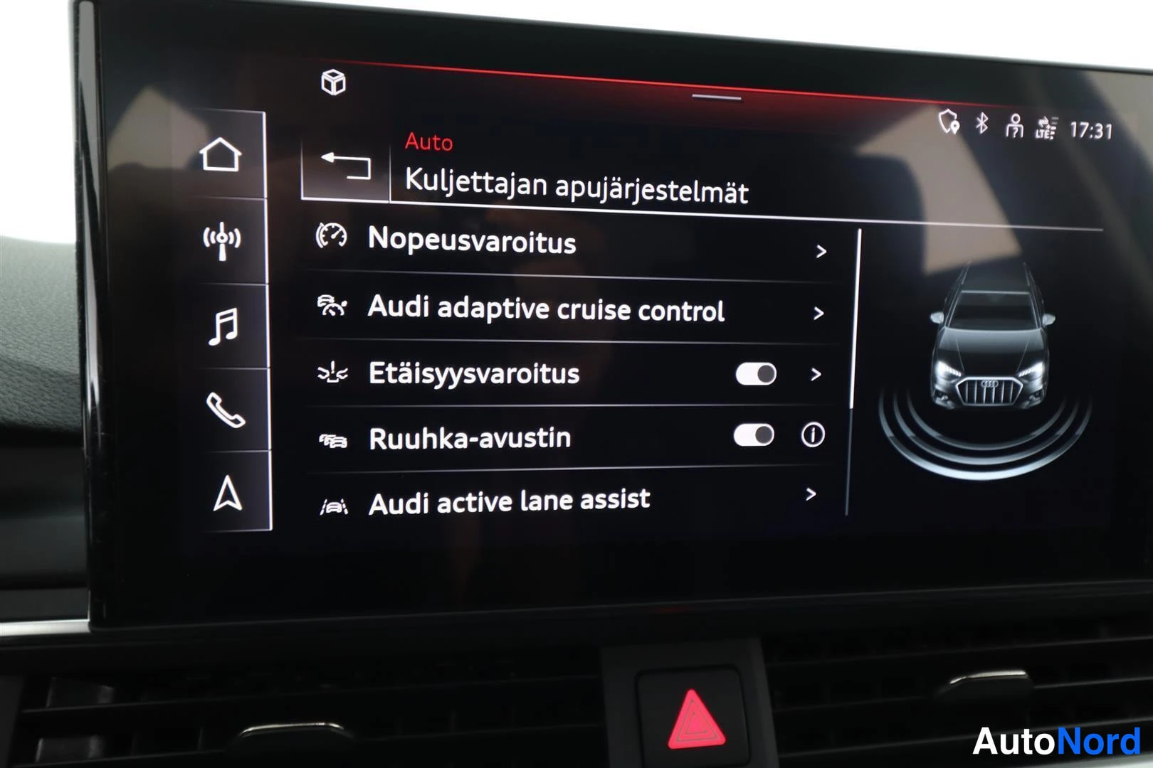 Muu: Audi-näyttö kuljettajan apujärjestelmät -valikko, jossa näkyvissä nopeusvaroitus, adaptive cruise control, etäisyysvaroitus, ruuhka-avustin ja active lane assis