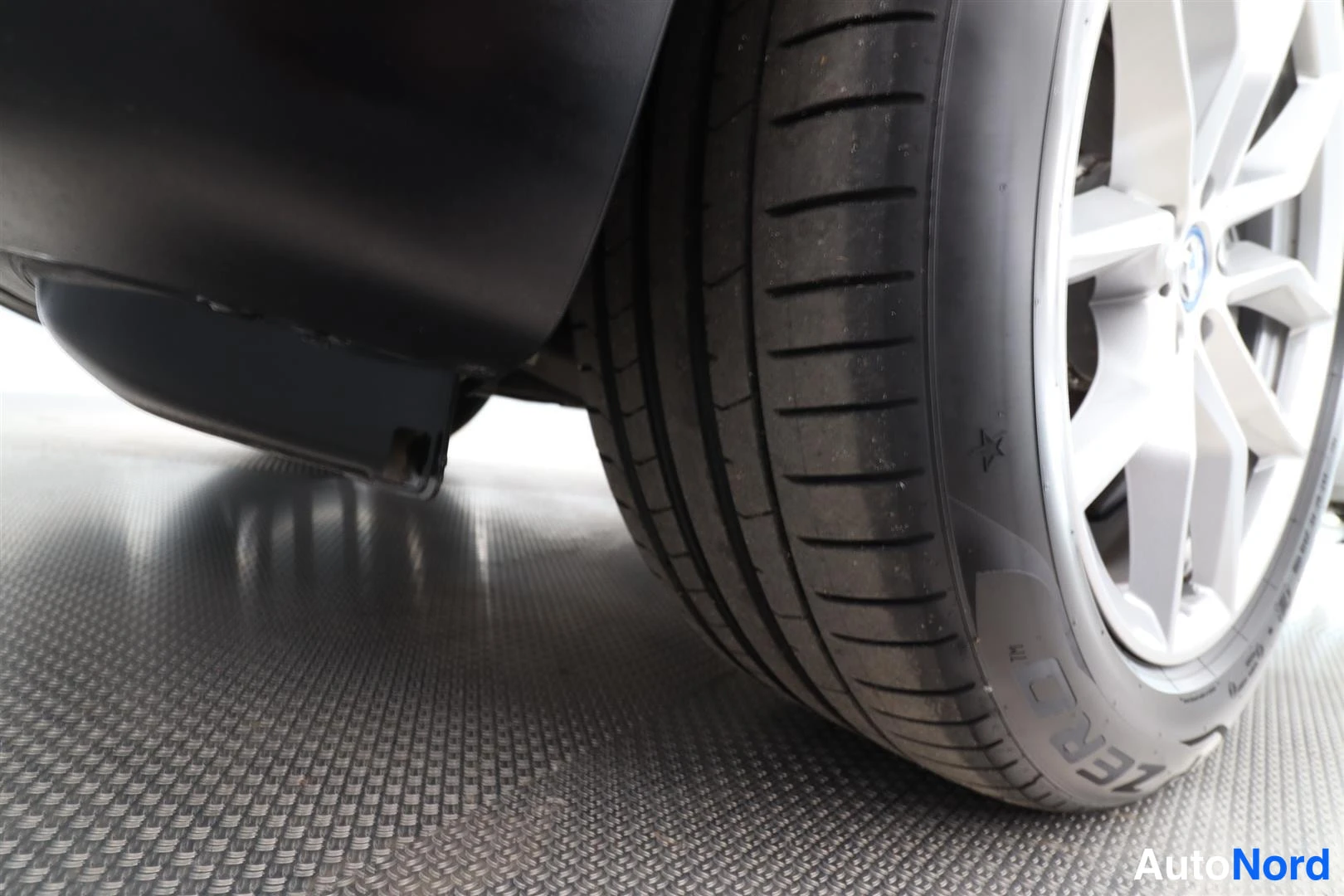 Yksityiskohta: Yksityiskohta auton pyörästä: hopea vanteen puolikas näkyy ja musta Pirelli-renkuksen sivuseinä, jossa P ZERO -merkintä.