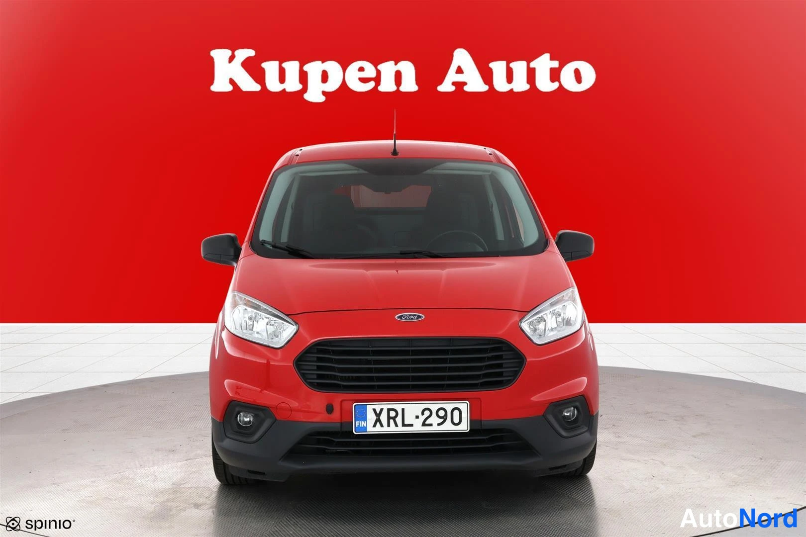 Edestä: Punaisen Ford Transit Courierin etunäkymä suoraan edestä, rekisteri punaisella taustalla.