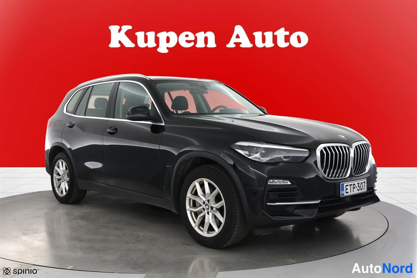 Etuviisto, nokka oikealle: BMW X5 -maastauto etu-kolmasosakulmasta, keulanäytösuunta vasemmalle, musta koripinta, punainen tausta.