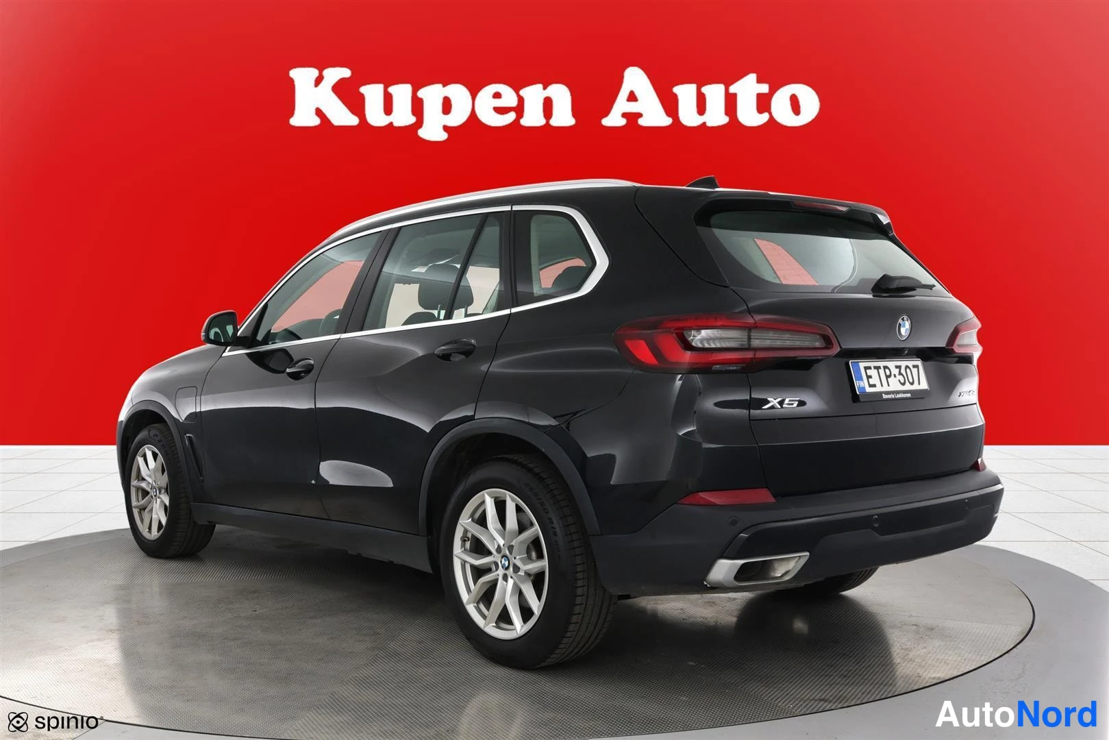 Takaviisto: BMW X5 taka-kolmasosakulmasta, takavalot ja X5-merkintä näkyvät, musta kori, punainen tausta.