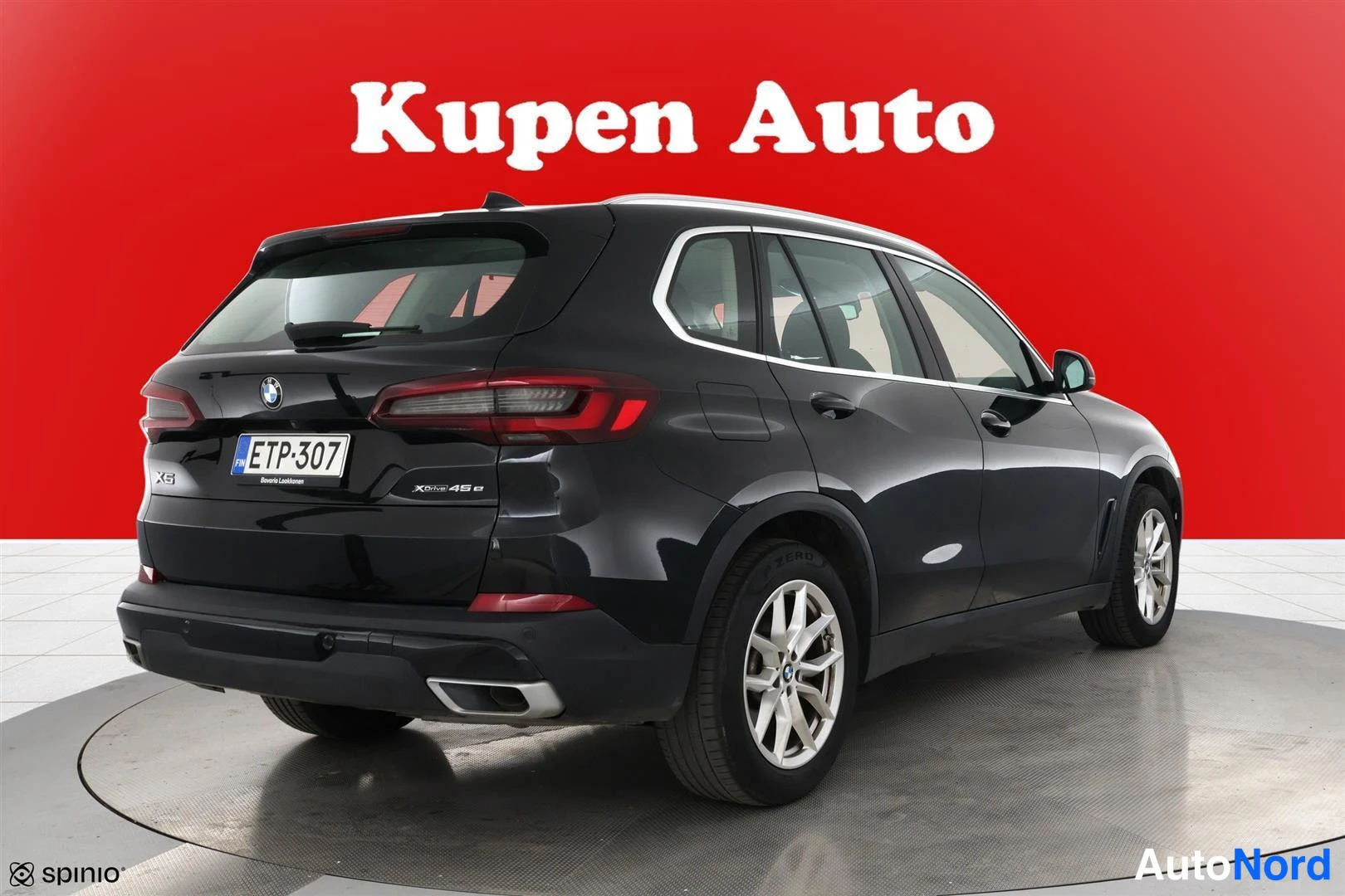 Takaviisto: Mustan BMW X5:n takakolmannes vasemmalta, hopeat vanteet, punainen tausta.