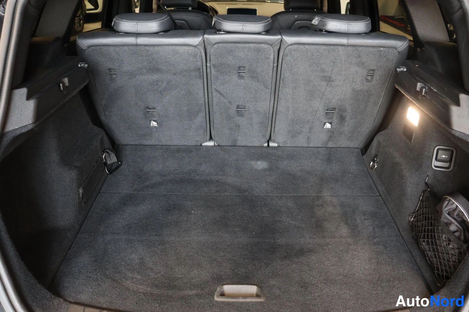 Tavaratila: Avattu tavaratila, takaselkänojät taitettuna, tummat matot ja ISOFIX-merinnät