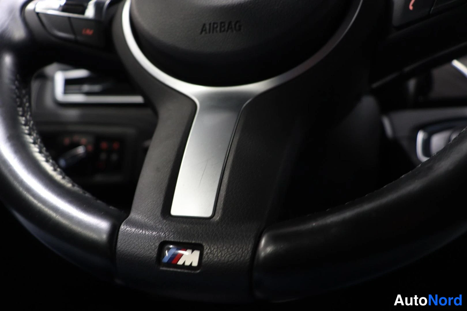 Yksityiskohta: BMW-ohjauspyörän keskusta M-merkillä ja AIRBAG-tekstillä.