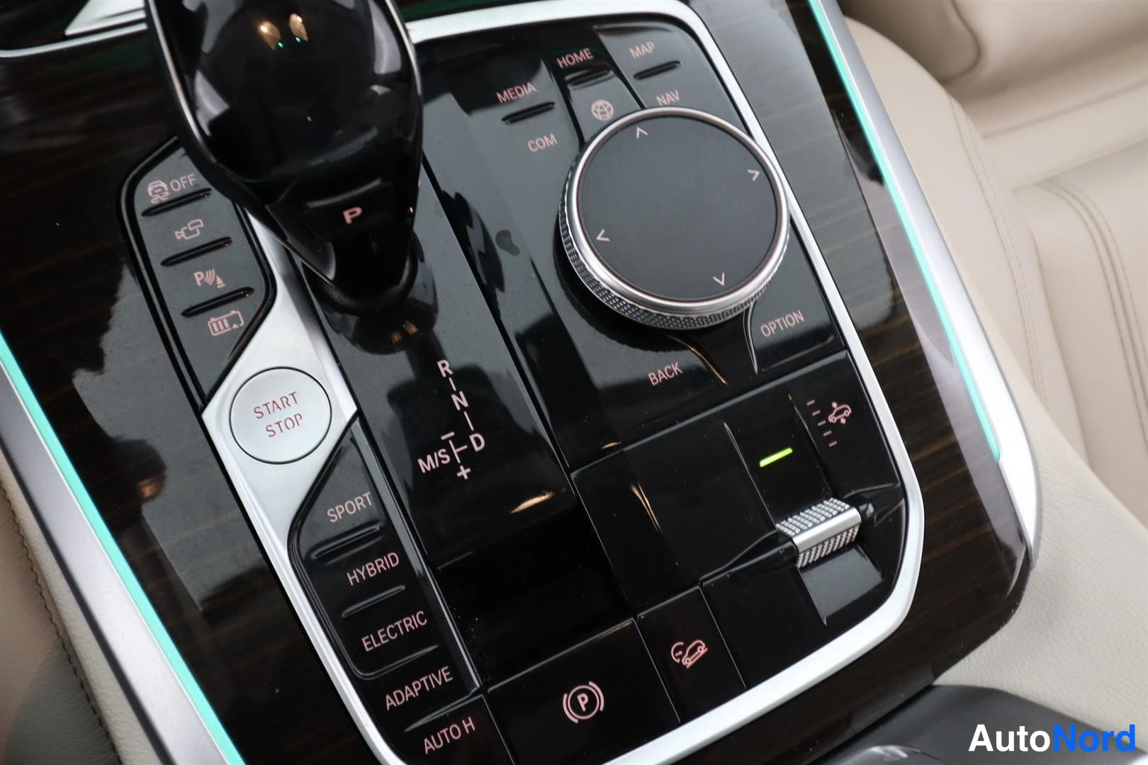 Yksityiskohta: Keskiöconsolin vaihtajan ja iDrive-ohjaimen lähikuva: START STOP -painike, ajotilat SPORT, HYBRID, ELECTRIC, ADAPTIVE ja AUTO H, pysäköintitunnistuksen ja kamer