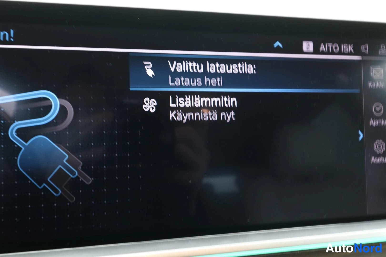 Yksityiskohta: Auton näyttö latausvalikossa: 'Valittu lataustila: Lataus heti' ja 'Lisälämmitin - Käynnistä nyt'.