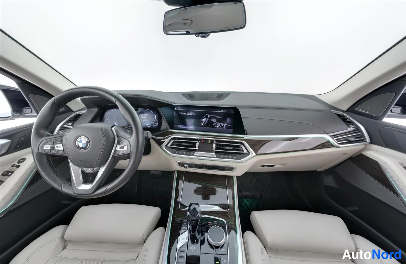 Ohjaamo: Ohjaamo kokonaisuudessaan: BMW-ohjauspyörä, kojelauta ja infotainment-näyttö, vaaleat istuimet.