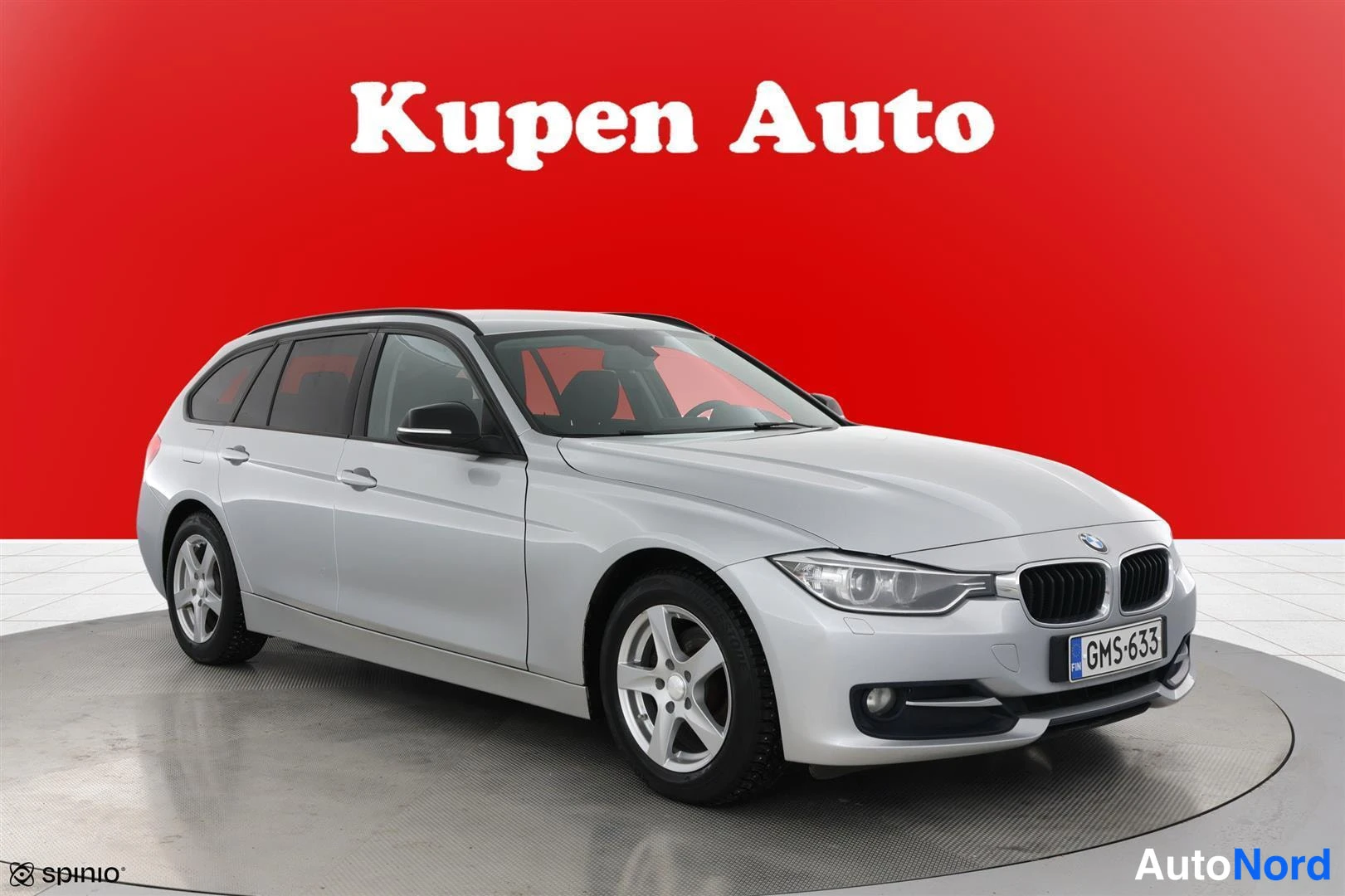 Etuviisto, nokka oikealle: Hopeanharmaa BMW 320 Touring -farmari punaisella taustalla, kolmen neljäsosan etunäkymä oikealta.