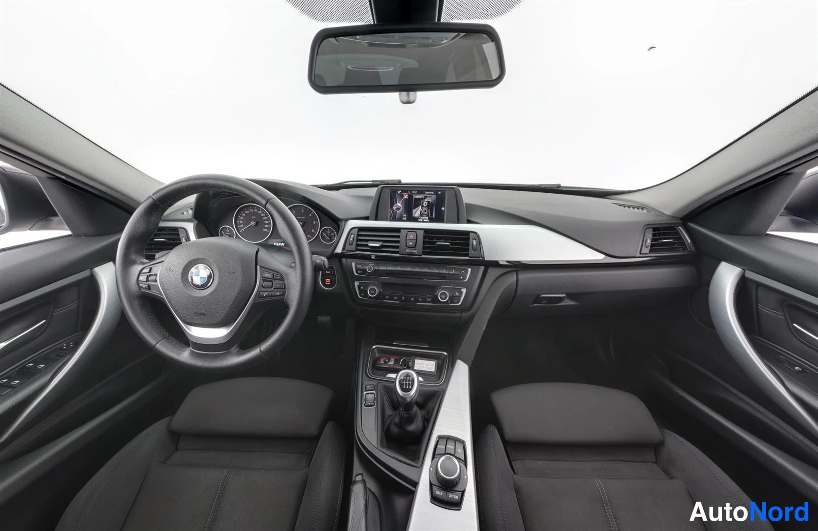 Ohjaamo: BMW:n ohjaamo etureunasta kuvattuna: ratinBMX-logo, mittarit, keskikonsolin näyttö ja manuaalivaihde.