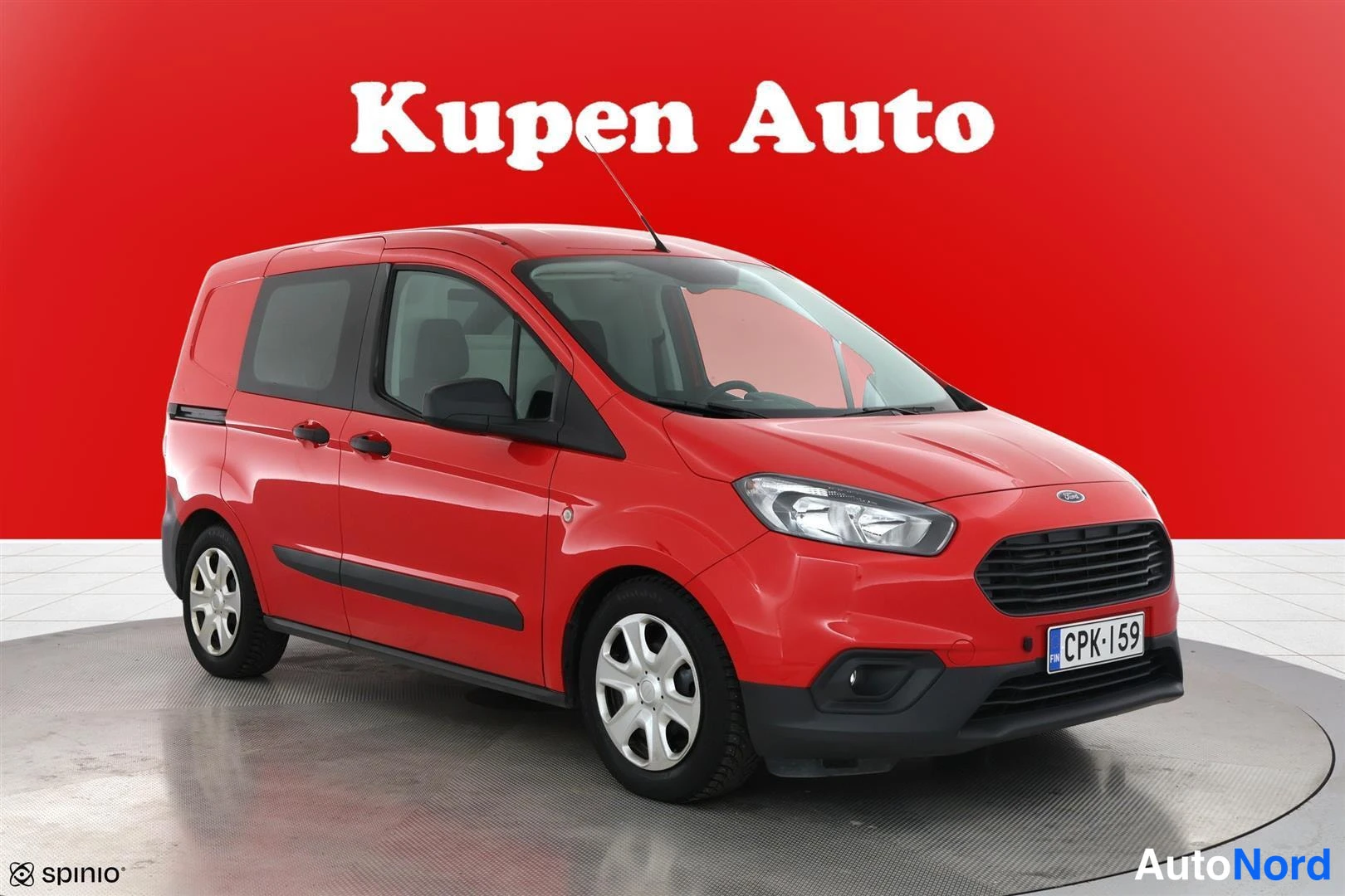 Etuviisto, nokka oikealle: Punainen Ford Transit Courier etukulmasta oikealta, kokonaisauto näkyvissä studio­taustalla.