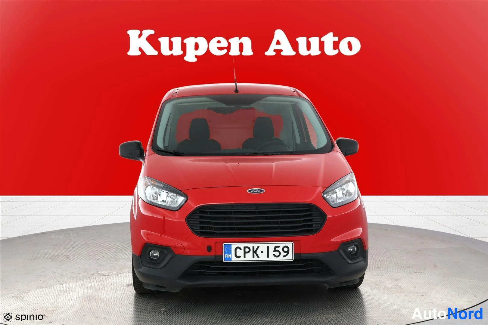 Edestä: Punainen Ford Transit Courier suoraan edestä, rekisterikilpi.