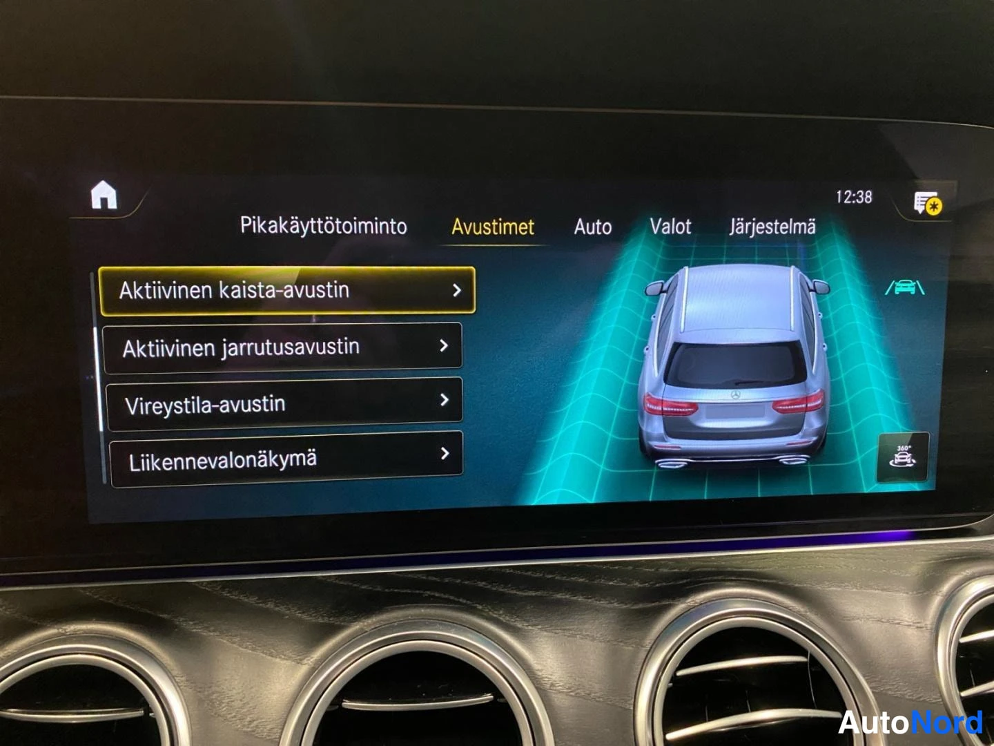 Ohjaamo: Keskinäytön Avustimet-valikko: Aktiivinen kaista-avustin, jarrutusavustin, vireystila-avustin ja liikennevalonäkmä.