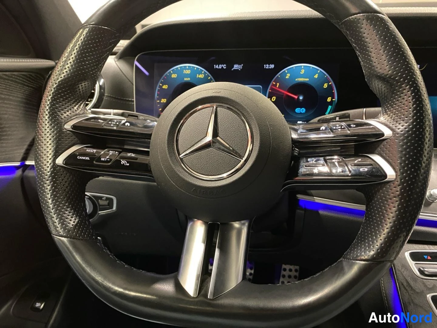 Sivulta: Ohjauspyörän ja digitaalisen mittariston sisäkuva: Mercedes-tähti ja AMG-teksti ohjauspyörässä, näytöllä 14,0 °C, kello 12:39 ja EQ-merkintä.