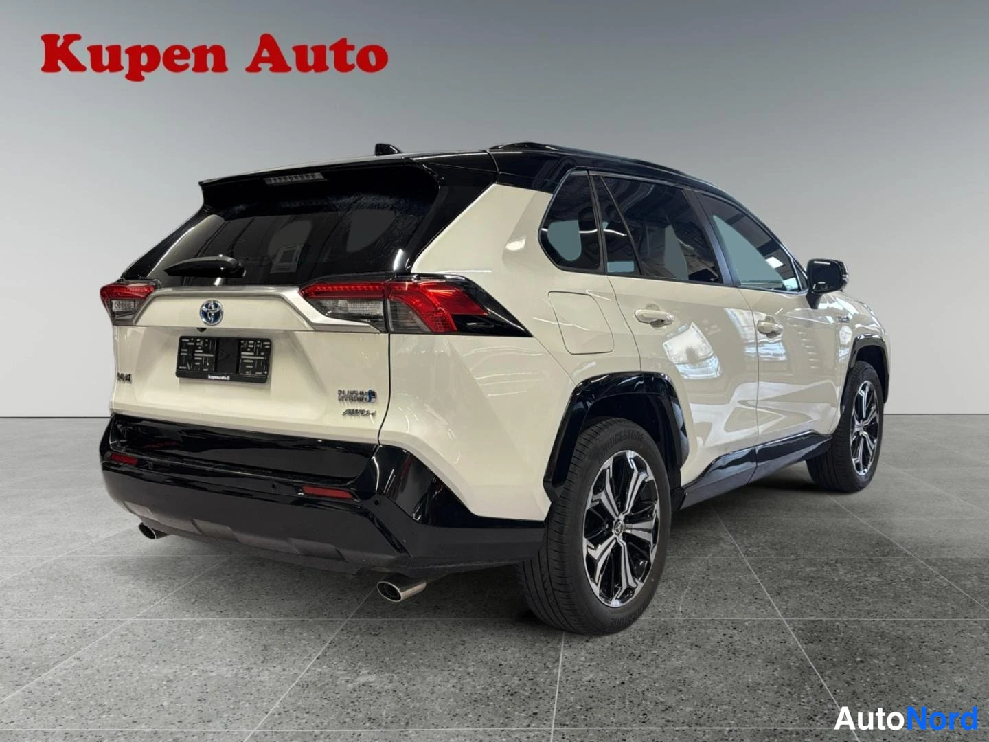 Takaviisto: Valkoinen Toyota RAV4, takakulmanäkymä vasemmalta, musta katto, takavalot ja pakoputki näkyvissä.