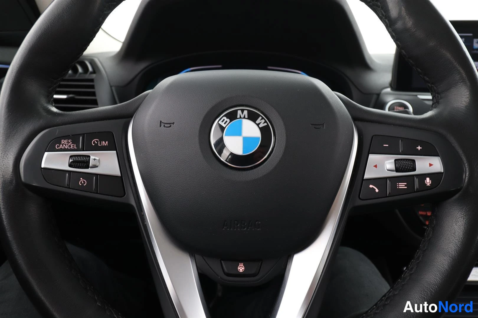 Yksityiskohta: BMW-ohjauspyörä, jossa monitoiminapit, RES CANCEL ja LIM -napit sekä AIRBAG-teksti.