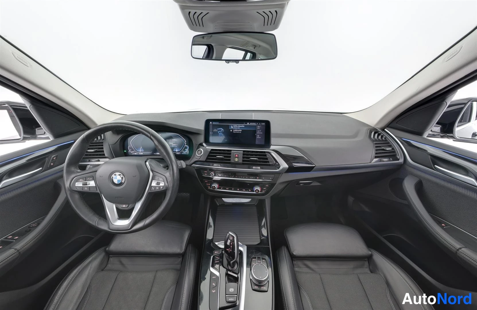 Ohjaamo: Ohjaamo etualalta: BMW-ohjauspyörä, digitaalinen mittaristo, navigointinäyttö ja tummat istuimet.